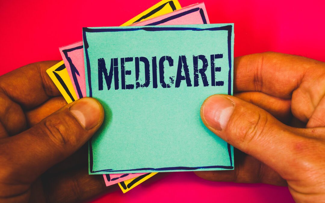 Close-up of hands holding a turquoise card labeled "MEDICARE" with colorful background cards, against a bright pink backdrop