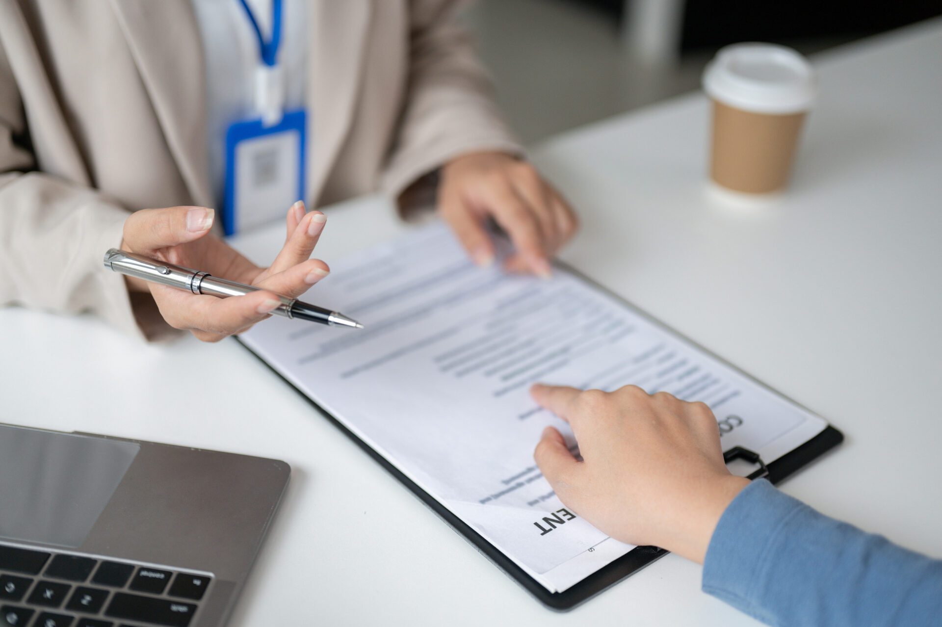 Two people reviewing a Medigap insurance contract with a pen and clipboard at a desk.