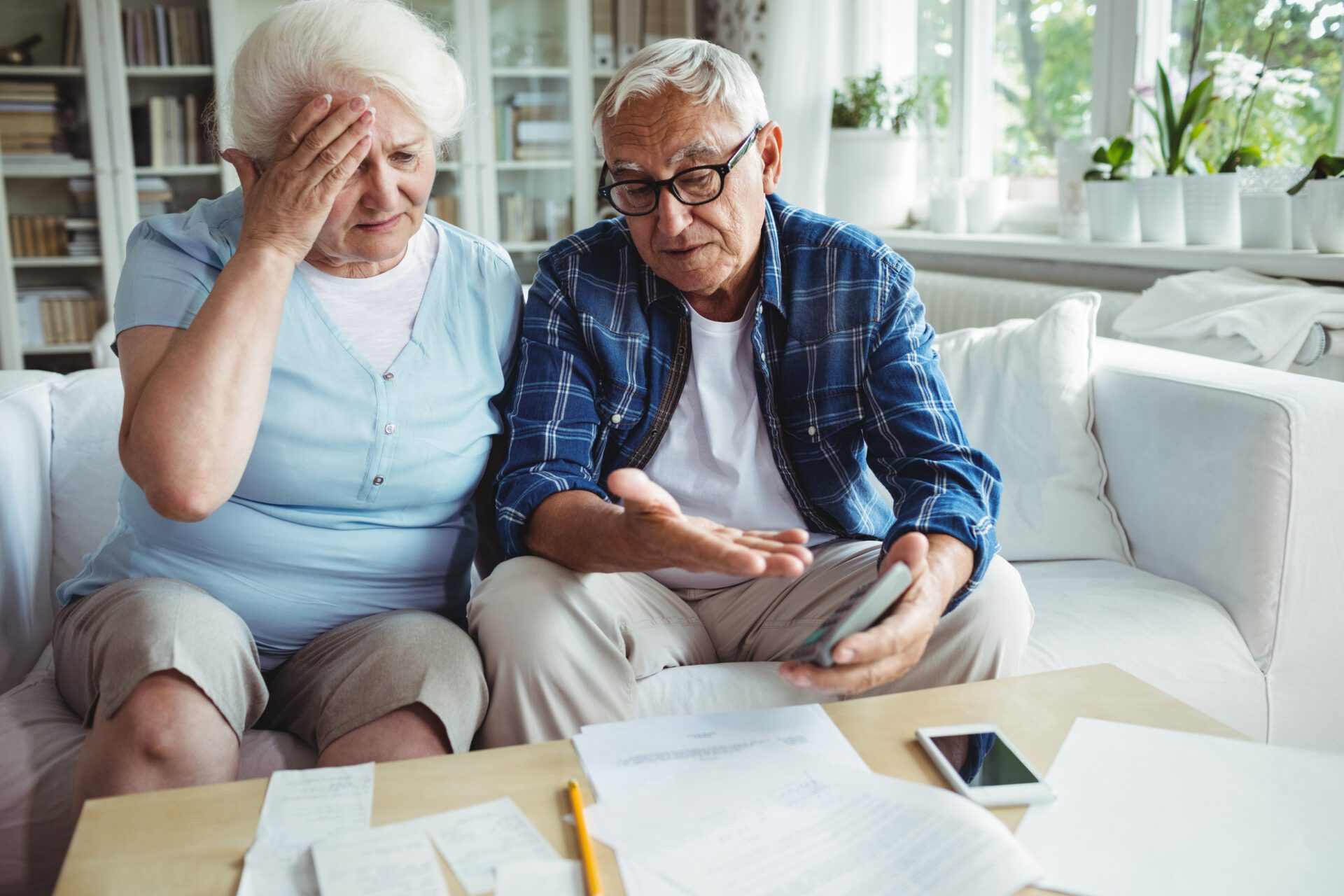 An image of an older couple sitting on a couch, reviewing financial documents.