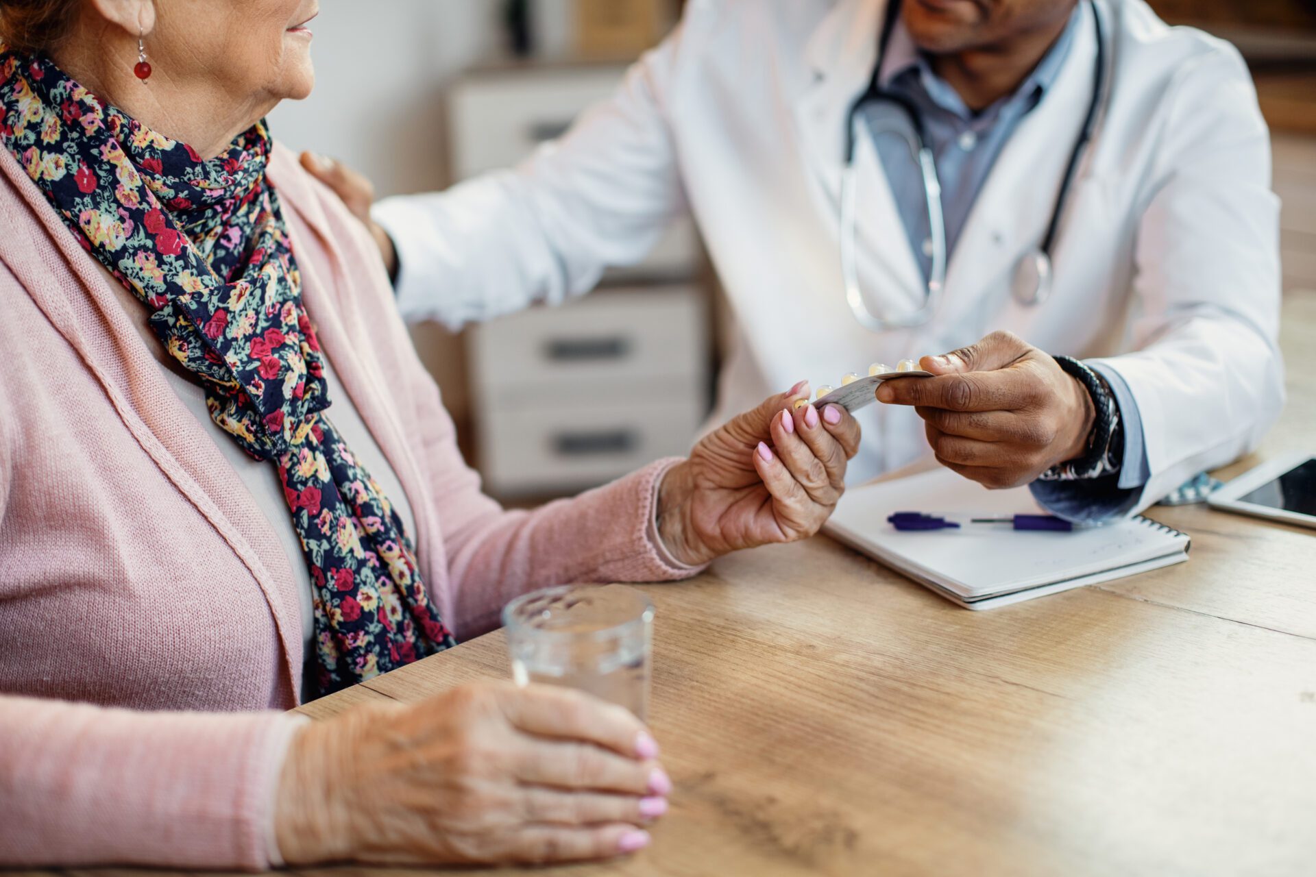 Doctor handing pills to a senior patient.