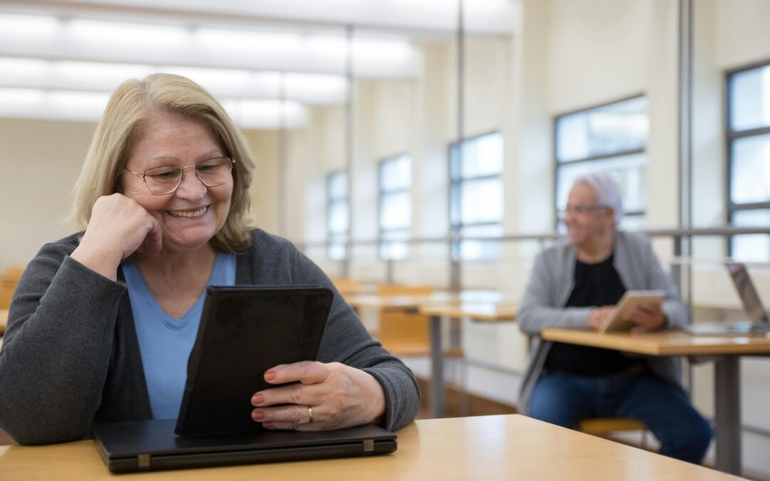 A woman sitting on table holding a digital tablet.